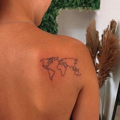 the back of a woman's shoulder with a small world map tattoo on it