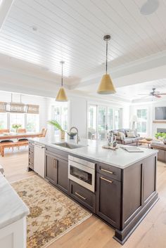 a large kitchen with an island in the middle and two pendant lights hanging from the ceiling