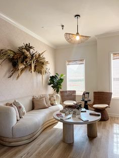 a living room filled with furniture and a plant hanging on the wall over the coffee table