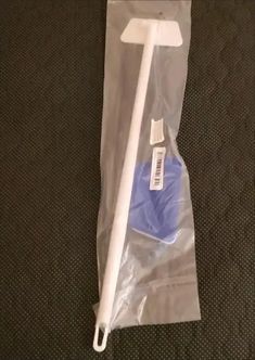 a white toothbrush in a plastic bag on the floor