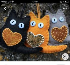 three felt cats hanging from a string on a rock with the word love spelled below them