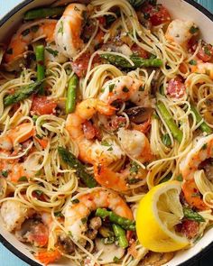 pasta with shrimp, asparagus and tomatoes in a skillet on a blue table