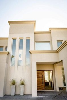 a large white house with two planters on the front and one door in the back