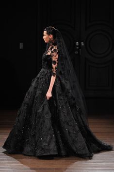 a woman in a black wedding dress on the runway