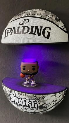 a basketball with a popfit figurine on it next to a purple and white ball