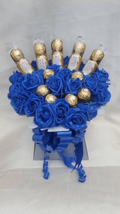 a bouquet of blue roses and chocolates in a card board with ribbon around it