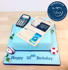 a blue birthday cake with a newspaper and cell phone on top