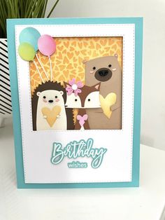 a birthday card with two bears and a bear holding a heart, on top of a table next to a potted plant