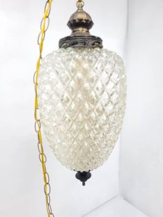 a glass light hanging from a chain on a white wall in a room with yellow trimmings