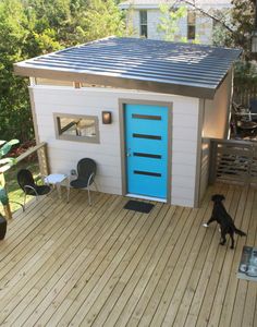 a dog is standing in front of a blue door on a small white house with a deck