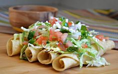 tortilla wrap filled with lettuce, tomatoes and other toppings on a wooden cutting board