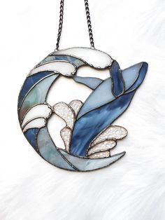 a blue and white stained glass bird hanging from a chain on a white furnishing