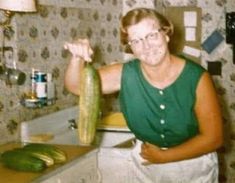 an old photo of a woman holding a cucumber