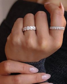 a woman's hand with two wedding bands on her left and one ring on her right