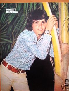 an old photo of a young man holding a surfboard in front of palm trees