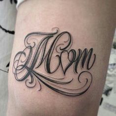 a tattoo with the word mom written in cursive writing on it's thigh