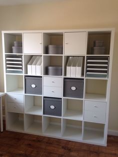 a white bookcase filled with lots of boxes and bins on top of it