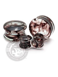 three different types of glass plugs on a white background, one with black and brown swirl