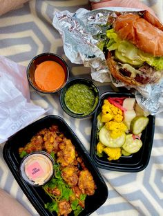 a person is laying down with some food on their lap and there are two trays full of food