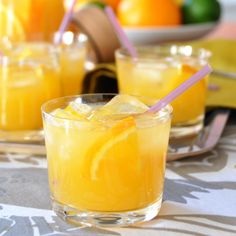 two glasses filled with orange juice and garnished with straws on a table