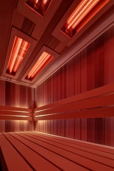 an empty room with wooden floors and red lighting on the ceiling is seen in this image