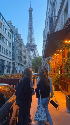 two women standing next to each other in front of the eiffel tower at dusk