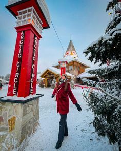 a woman standing in the snow next to a red sign that says hotel cource