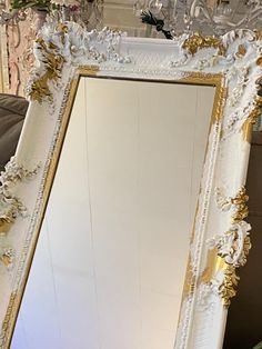 an ornate white and gold framed mirror in a living room