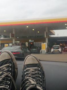 a pair of shoes that are sitting in front of a gas station with cars passing by