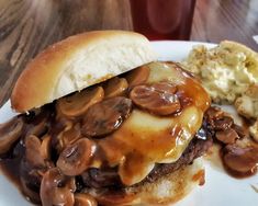 a hamburger covered in mushrooms sitting on top of a white plate