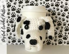 a crocheted coffee cup holder with a black and white dog's face