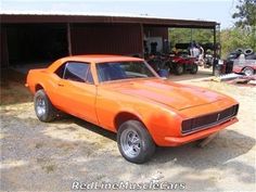 an orange muscle car parked in front of a garage