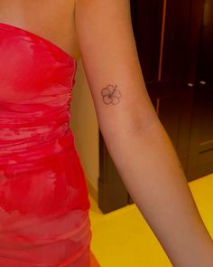 a woman's arm with a small flower tattoo on the left side of her arm