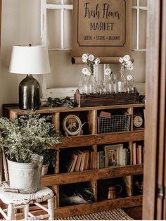 a wooden shelf filled with lots of books next to a white lamp and window sill