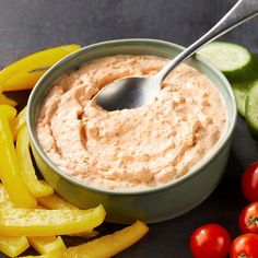 a bowl of dip surrounded by vegetables and sliced cucumbers