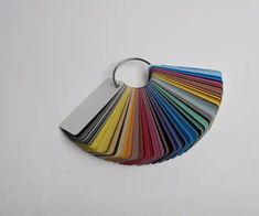 a bunch of different colors of paper on a white surface with a metal keychain