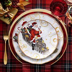 a plate with santa clause on it sitting on a plaid table cloth next to silverware