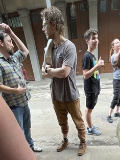 a group of young men standing around each other in front of a building and talking