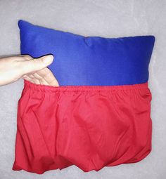 a person is holding onto a pillow with red and blue material on the bottom half