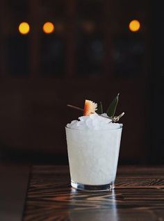 a glass filled with ice and garnish on top of a table