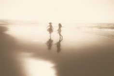 two girls are walking on the beach together