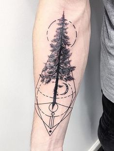 a man's arm with a compass and pine tree tattoo on the left forearm