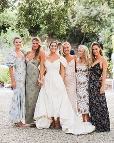 a group of women standing next to each other wearing dresses and smiling at the camera