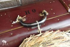 an old red suitcase is sitting on some straw