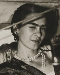 an old black and white photo of a woman with pearls on her necklace looking down