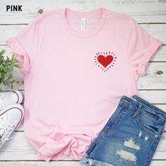 Our simple, hand drawn red heart shirt is the perfect shirt to celebrate love - great for Valentine's Day, Bachelorette Parties, or Bridal Party and Flower Girl Gifts.   Our shop uses direct-to-garment printing to make our products. The design ink is sprayed on, then allowed to soak into the fibers of the garment. This process yields fine quality prints and a smooth finish on the garment. BELLA + CANVAS T SHIRT The Bella + Canvas 3001 t-shirt feels soft and light, with just the right amount of stretch. It's comfortable and the unisex cut is flattering for both men and women. We can't compliment this shirt enough - it's one of our crowd favorites. And it's sure to be your next favorite too! SIZING Most customers feel this shirt fits true to size. This shirt is relaxed/loose fit and will be Pink Heart-shaped T-shirt For Summer, Cheap Pink T-shirt With Heart Print, Relaxed Fit Pink T-shirt With Heart Graphic, Pink Cotton T-shirt With Heart Graphic, Heart-shaped T-shirt For Valentine's Day, Pink Heart Print T-shirt For Valentine's Day, Bridal Bachelorette Party, Flower Girl Gifts, Heart Shirt