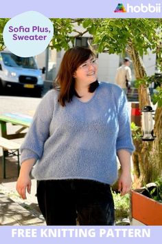 a woman standing in front of a tree wearing a blue sweater and black pants with the words free knitting pattern