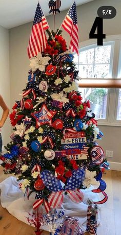 a woman standing next to a christmas tree decorated with red, white and blue decorations