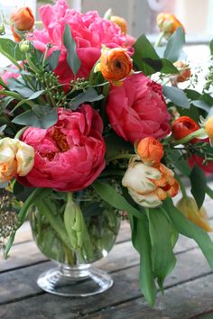 a vase filled with lots of flowers on top of a wooden table