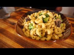 a bowl filled with pasta and broccoli on top of a wooden table